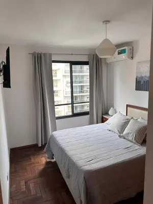 a bedroom with a bed and a large window at Obispo Oro Departamento Temporario Córdoba in Cordoba