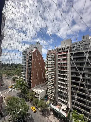 a view of two tall buildings from behind a fence at Obispo Oro Departamento Temporario Córdoba in Cordoba