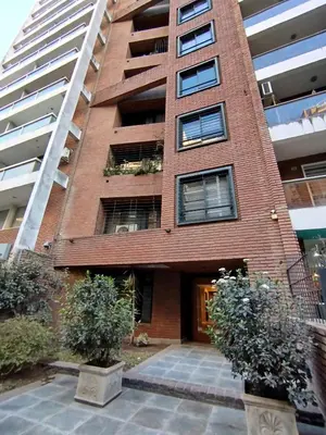 a red brick building with two trees in front of it at Obispo Oro Departamento Temporario Córdoba in Cordoba