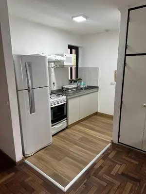 a kitchen with a white refrigerator and a wooden floor at Obispo Oro Departamento Temporario Córdoba in Cordoba