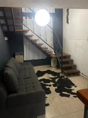 a living room with a couch and a staircase at Departamento en plena peatonal de Carlos Paz in Villa Carlos Paz