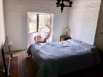 a bedroom with a bed and a chair and a window at Púrpura Atardecer Hermosa casa de montaña in San Javier