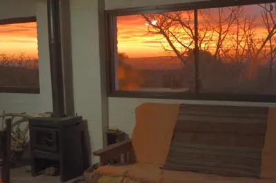 a living room with a chair and a fireplace with a sunset at Púrpura Atardecer Hermosa casa de montaña in San Javier