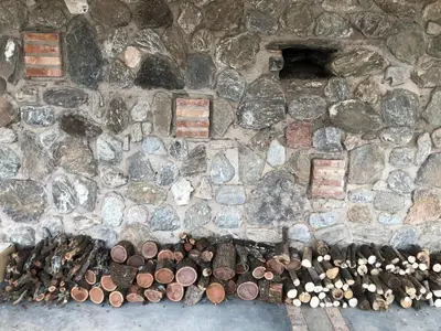 a stone wall with a pile of wood and a fire at Púrpura Atardecer Hermosa casa de montaña in San Javier