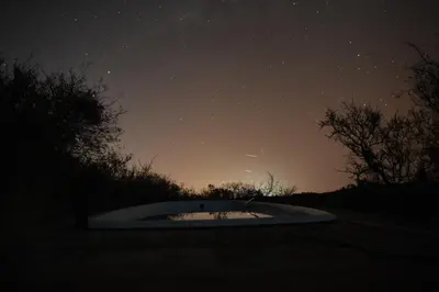 a starry night with a small crater in the middle of a field at Púrpura Atardecer Hermosa casa de montaña in San Javier