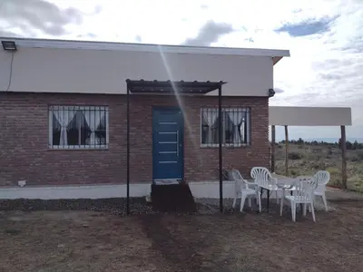 a house with a table and chairs and a blue door at Portal del Sol in Villa Yacanto