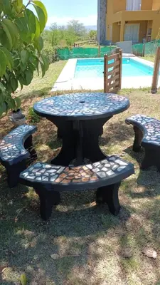 a picnic table with three benches next to a pool at Cabaña Malibu in Los Reartes