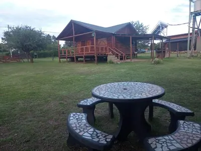 a picnic table and benches in front of a cabin at Cabaña Malibu in Los Reartes