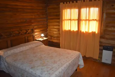 a bedroom with a bed in a log cabin at Cabaña Malibu in Los Reartes