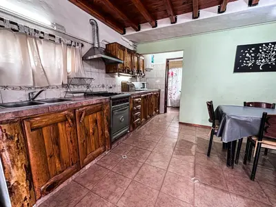 a kitchen with wooden cabinets and a table and a sink at Casa con pileta de uso exclusivo in Tanti