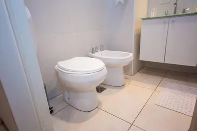 a white bathroom with a toilet and a sink at Departamento en Nueva Córdoba in Cordoba