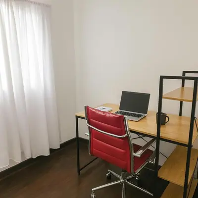 a red chair sitting at a desk with a laptop at Atenea Residence in Cordoba