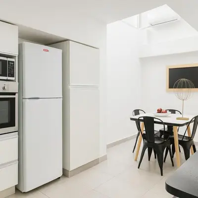 a white kitchen with a table and a refrigerator at Atenea Residence in Cordoba
