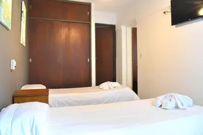 a bedroom with two beds with white sheets at Gran hotel argentino in Villa Carlos Paz