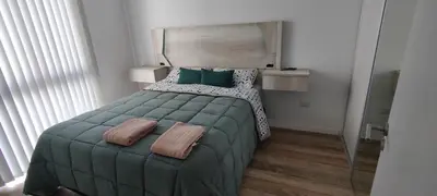 a bedroom with a bed with green sheets and pillows at Lake in Villa Carlos Paz