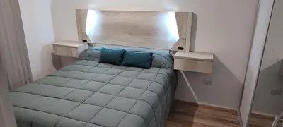 a small bedroom with a bed with blue pillows at Lake in Villa Carlos Paz