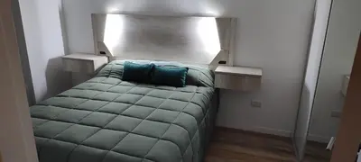 a small bedroom with a bed with blue pillows at Lake in Villa Carlos Paz
