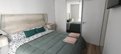 a small bedroom with a bed with green and white pillows at Lake in Villa Carlos Paz