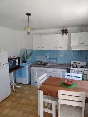 a kitchen with white cabinets and a wooden table at La casita azul, Tanti in Tanti
