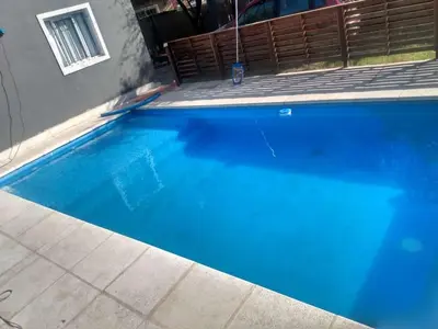 a large blue swimming pool next to a house at Cabañas La Mimi in Villa Anizacate