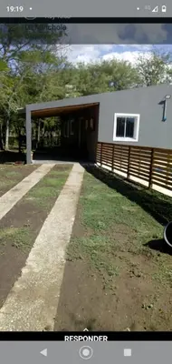 a house with a garage and a grassy yard at Cabañas La Mimi in Villa Anizacate