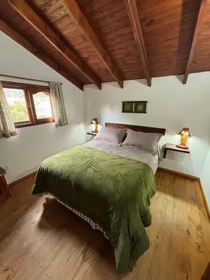 a bedroom with a bed with a green comforter at Cabañas Rio Manso in La Cumbrecita