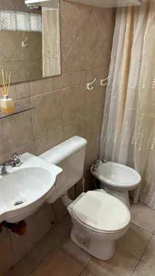 a bathroom with a white toilet and a sink at Cabañas Rio Manso in La Cumbrecita