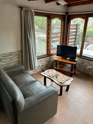 a living room with a couch and a tv at Cabañas Rio Manso in La Cumbrecita
