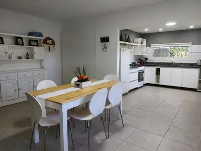 a kitchen with a wooden table and white chairs at Casa en Villa Amancay, Calamuchita in Villa Amancay