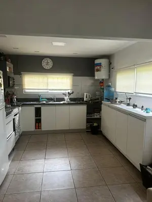 a kitchen with white cabinets and a clock on the wall at Casa en Villa Amancay, Calamuchita in Villa Amancay