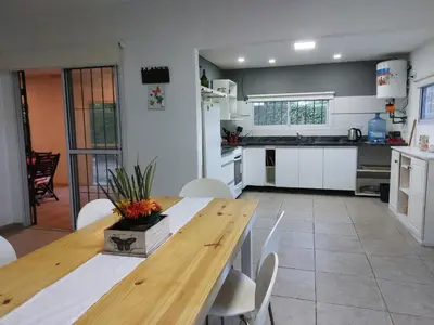 a kitchen with a wooden table and white cabinets at Casa en Villa Amancay, Calamuchita in Villa Amancay