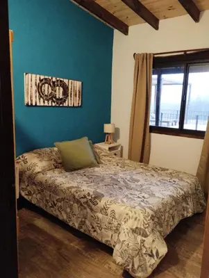 a bedroom with a bed and a blue wall at Gran Cabaña Dos Yacanto in Villa Yacanto