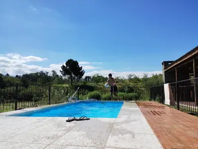 a man standing next to a swimming pool with a frisbee at Gran Cabaña Dos Yacanto in Villa Yacanto