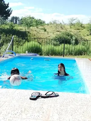 two people are swimming in a swimming pool at Gran Cabaña Dos Yacanto in Villa Yacanto