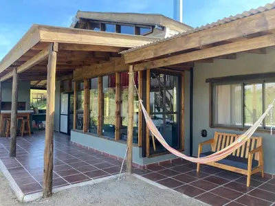a porch with a hammock outside of a house at Gran Cabaña Dos Yacanto in Villa Yacanto