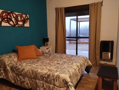a bedroom with a bed and a door to a balcony at Gran Cabaña Dos Yacanto in Villa Yacanto