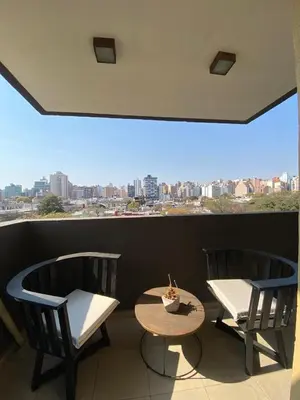 a balcony with two chairs and a table and a window at Dptos Córdoba -Guemes, Sobre la Cañada, vista al Paseo de Artesanos in Cordoba