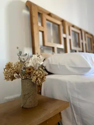 a vase with flowers on a table next to a bed at Dptos Córdoba -Guemes, Sobre la Cañada, vista al Paseo de Artesanos in Cordoba
