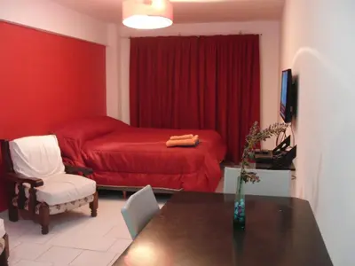 a red room with a bed and a chair and a table at Departamento Amoblado en Nueva Cordoba in Cordoba