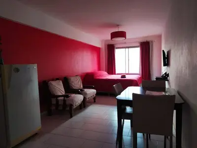 a living room with red walls and a table and chairs at Departamento Amoblado en Nueva Cordoba in Cordoba