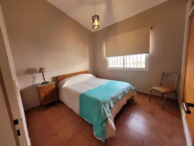 a bedroom with a bed and a chair and a window at Casa Tío Luis in Villa Carlos Paz