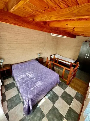 a bedroom with a purple bed in a wooden room at Cabañas Maranatha in El Rincón