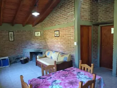 a living room with a table and a brick wall at Estancia La Victoria - Cabañas de Montaña in Villa Yacanto