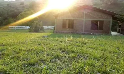 a house with the sun shining on a yard at Estancia La Victoria - Cabañas de Montaña in Villa Yacanto