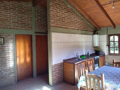 a kitchen with a table and a brick wall at Estancia La Victoria - Cabañas de Montaña in Villa Yacanto