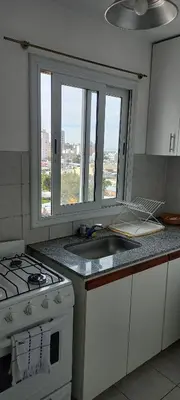 a kitchen with a stove and a sink and a window at Cómodo Dpto Colón 600 in Río Cuarto
