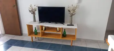 a tv on a table with two vases on it at Cómodo Dpto Colón 600 in Río Cuarto