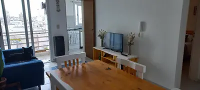 a living room with a tv and a wooden table at Cómodo Dpto Colón 600 in Río Cuarto