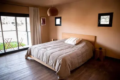 a bedroom with a bed and a large window at Cueva de lujo con rio de montaña Casa cueva in Villa Cura Brochero