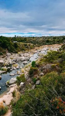 a river in the middle of a field with rocks at Cueva de lujo con rio de montaña Casa cueva in Villa Cura Brochero